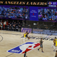 Two teams play in a nearly empty arena in front of a large video screen displaying the heads of virtual fans.